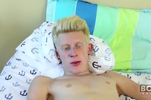 Erotic nude guy is lying on a bed with a dildo in his butt and dick in his hands